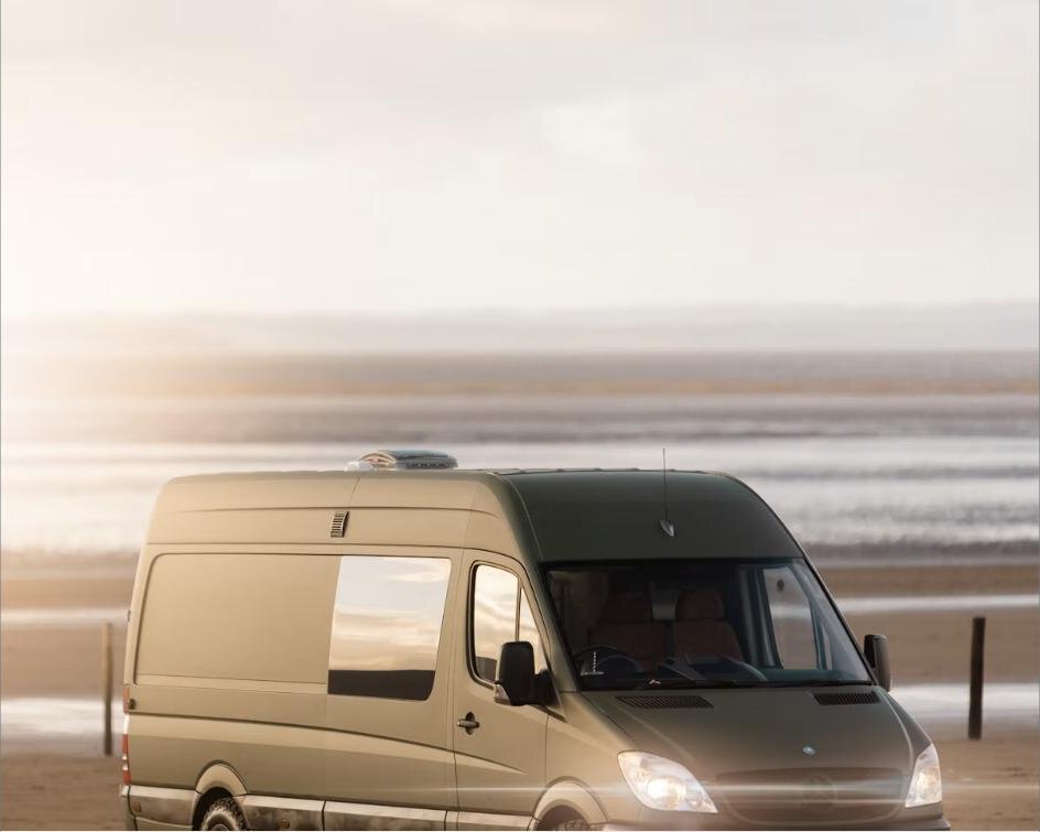 Campervan parked on a beach at sunset, sea in the background