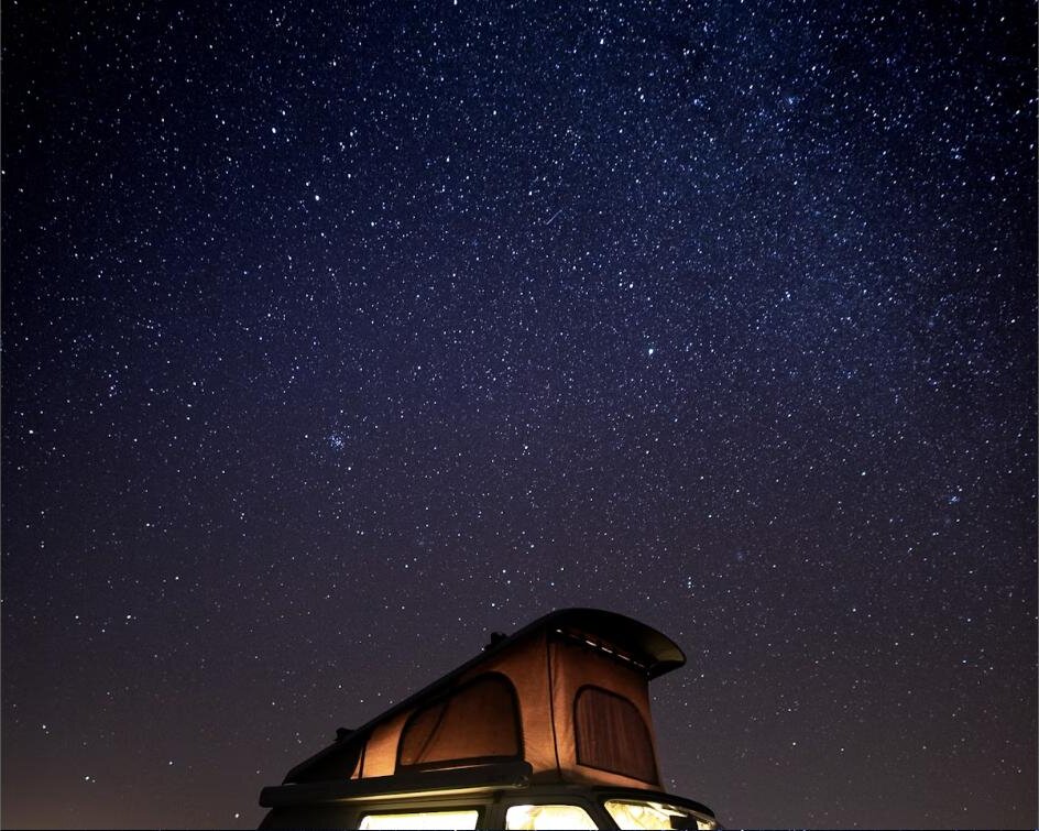 Pop-top camper roof lit up under a starry night sky