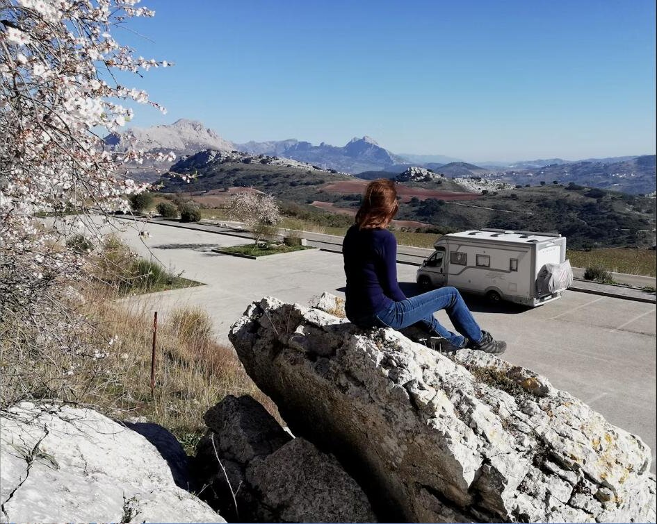 Motorhome parked on a scenic mountain road, snow-capped peaks in the background